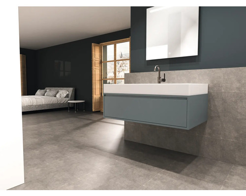 Salle de bains moderne avec meuble sous-lavabo, miroir et lit en arrière-plan.