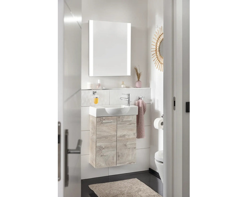 Salle de bains lumineuse avec lavabo, armoire de toilette éclairée et toilettes