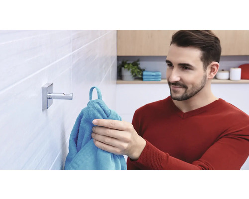 Mann hängt Handtuch auf Handtuchhaken im Badezimmer