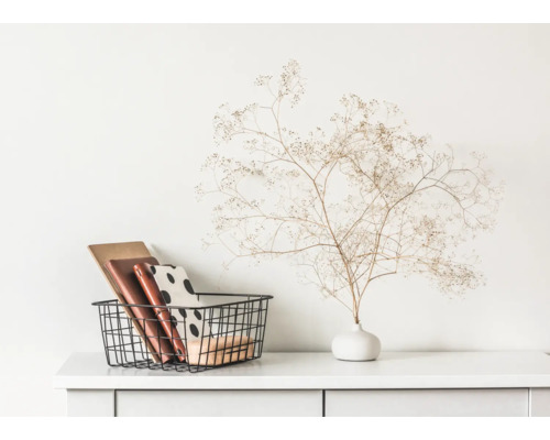 Dekorative Aufbewahrungskörbe mit Büchern und Vase mit Trockenblumen auf weißer Kommode