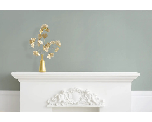 Dekorative goldene Ginkgozweige in Vase auf weißem Kaminsims