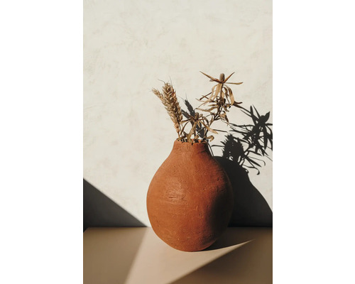 Vase décorative en argile avec fleurs séchées sur une table