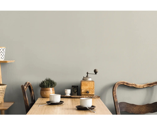 Wohnraum mit Tisch, Stühlen und Dekoration vor einer grauen Wand