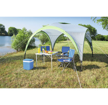 Scène de camping avec tonnelle, table, chaises et glacière sur une pelouse au bord d''un lac