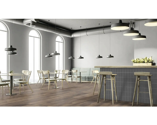 Innenansicht eines Restaurants mit Tischen, Stühlen, einer Bar und Pendelleuchten