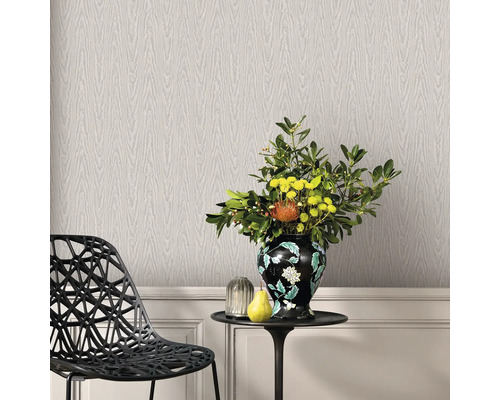 Dekoratives Interieur mit Tapete in Holzoptik, Stuhl und Tisch mit Blumenvase.