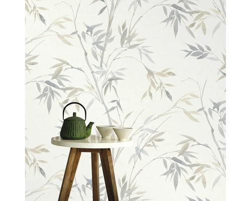 Dekorative Tapete mit Bambusmuster im Hintergrund, Teekanne und Schalen auf kleinem Tisch