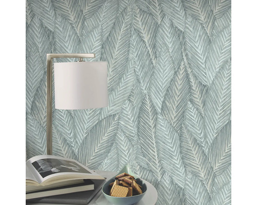 Dekorative Tapete mit Blattmuster, Tischlampe, Bücher und Schüssel mit Keksen