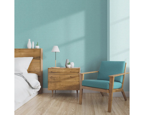 Helles Schlafzimmer mit Holzbett, Nachttisch, Lampe und Sessel