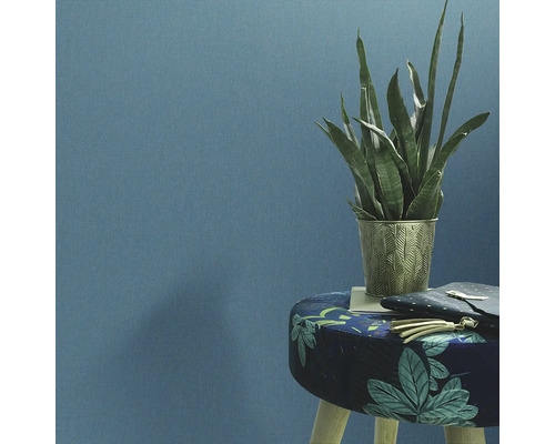 Plante d''intérieur décorative dans un pot ornemental sur un tabouret devant un mur.