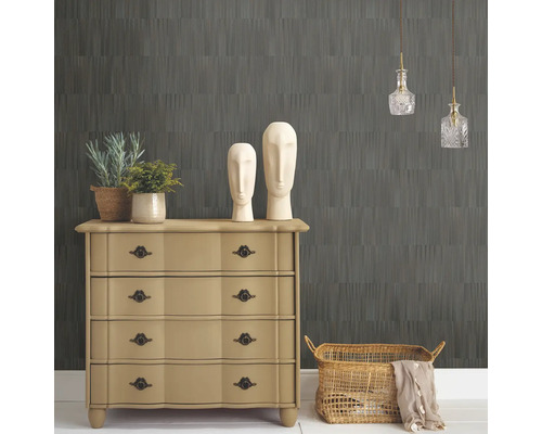 Raumansicht mit gemusterter Tapete, Kommode, Dekorationselementen und Beleuchtung