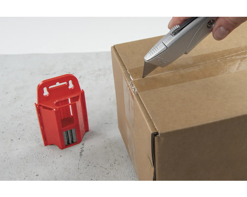 Ein Cuttermesser öffnet einen Karton neben einem roten Klingenmagazin.