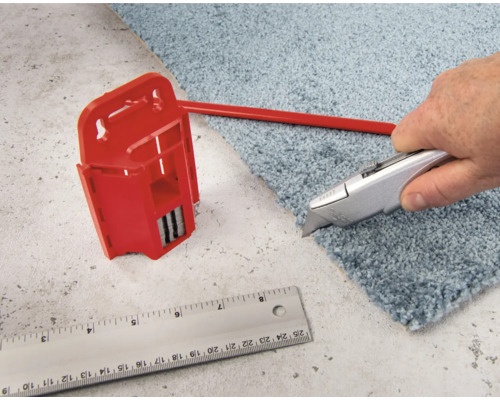 Teppichmesser schneidet Teppich neben Teppichschneider und Lineal