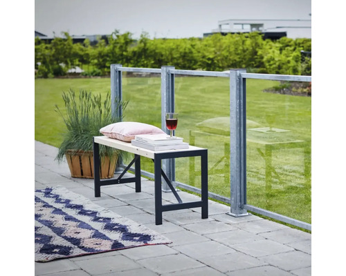Banc avec cadre en métal, coussin, livres et verre à vin sur une terrasse