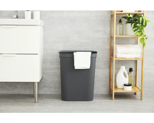 Badezimmer Szene mit einem grauen Wäschekorb mit Deckel, einem weißen Waschtisch und einem Holzregal