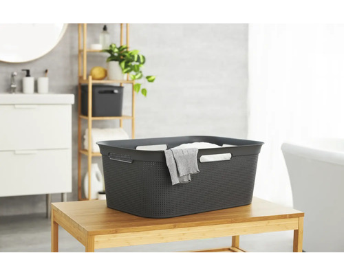 Wäschekorb aus Kunststoff auf Bambustisch in einem Badezimmer