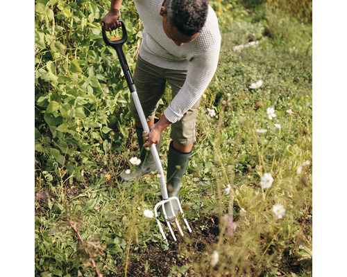 Un homme utilise une fourche à bêcher dans le jardin.