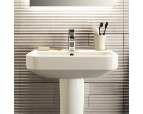 Lavabo avec colonne, robinet, savon et brosses à dents dans la salle de bain