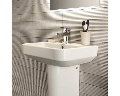 Lavabo en céramique avec robinet, savon, brosses à dents et porte-brosses à dents dans la salle de bain