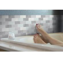 Badezimmerszene mit Fliesenaufklebern im Steinmuster und einer Person in der Badewanne