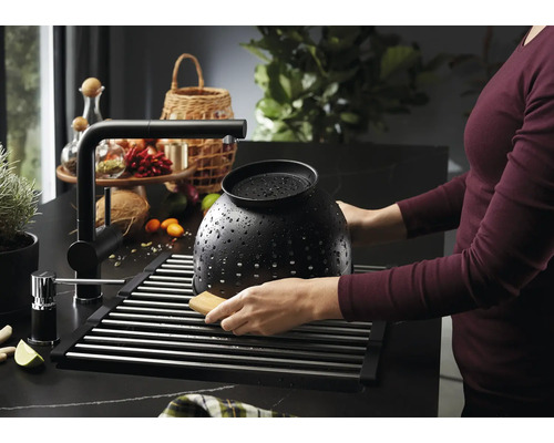 Évier avec égouttoir, robinet et personne nettoyant une passoire