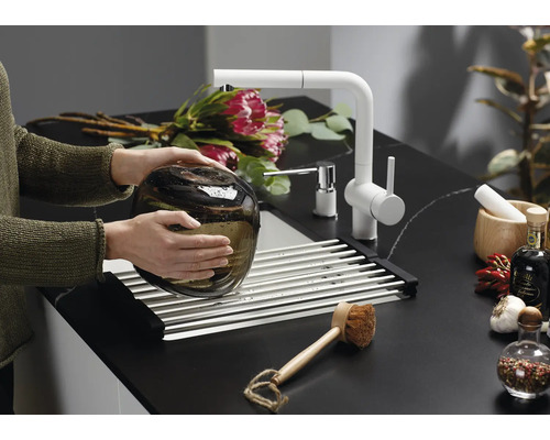 Scène de cuisine moderne avec robinet d''évier, égouttoir et éléments décoratifs sur un plan de travail foncé