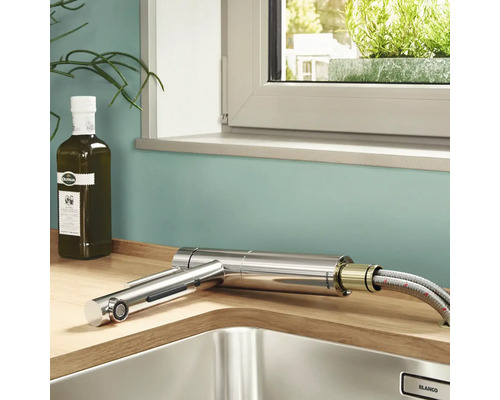 Évier de cuisine avec robinet extractible, bouteille d''huile d''olive et fenêtre en arrière-plan.