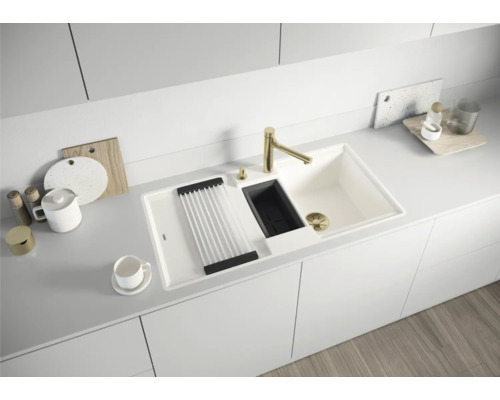 Évier de cuisine avec égouttoir, distributeur de savon et robinet doré dans une cuisine moderne.