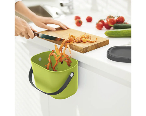 Scène de cuisine avec poubelle à déchets organiques verte, planche à découper et légumes