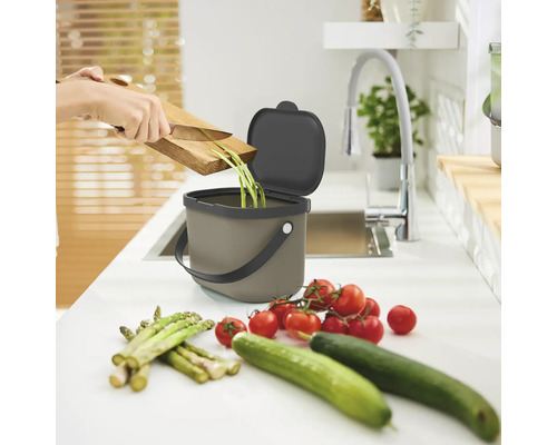 Poubelle à compost sur un plan de travail de cuisine avec des restes de légumes