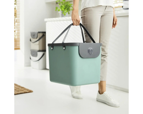 Femme portant un seau turquoise avec des poignées pour le tri des déchets