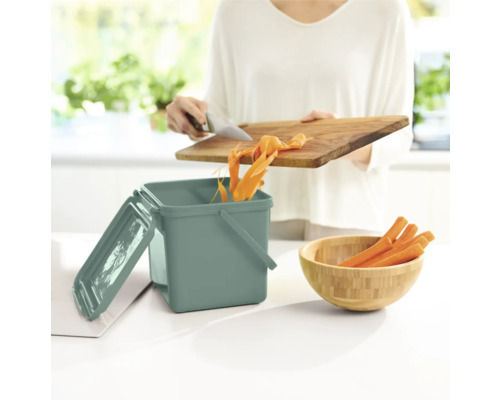 Küchenszene mit Komposteimer, Schneidebrett und Karotten