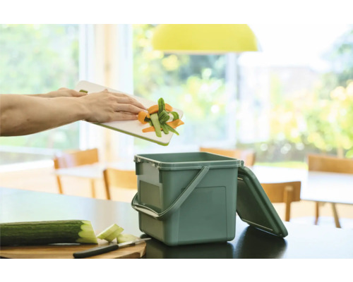 Gemüseabfälle werden in einen Komposteimer mit Deckel entsorgt.