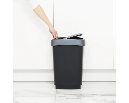 Person öffnet einen schwarzen Treteimer mit grauem Deckel.