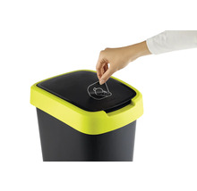 Une personne jette une bouteille dans une poubelle avec un symbole de recyclage