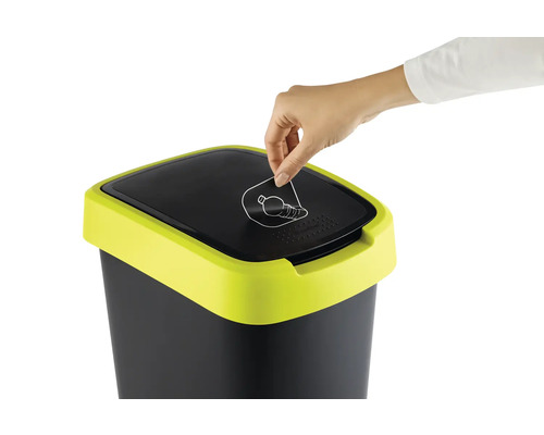 Une personne jette une bouteille dans une poubelle avec un symbole de recyclage