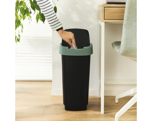 Une personne jette du papier dans une poubelle à couvercle basculant