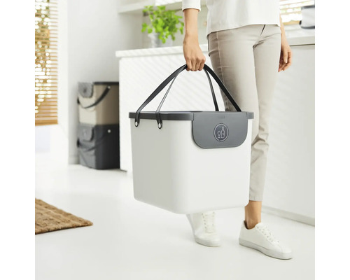 Une personne porte un bac de recyclage blanc avec un symbole de bouteille