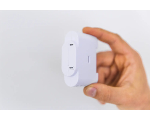 Une main tenant un capteur d''énergie Shelly blanc