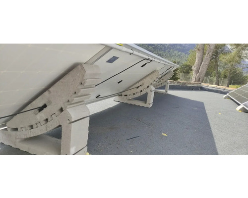 Aufgeständerte Solarmodule auf einem Dach mit Betonstützen.