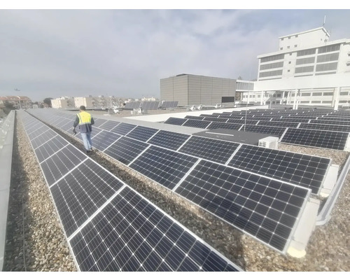 Aufnahme von Solarmodulen auf einem Dach mit einer Person, die eine Sicherheitsweste trägt