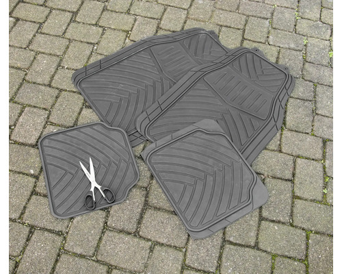 Vier schwarze Gummifußmatten für Autos liegen auf Pflastersteinen.