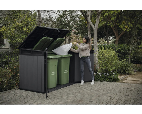 Mülltonnenbox mit Frau, die einen Müllsack hineinwirft, im Garten