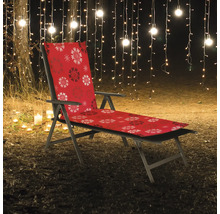 Gartensessel mit roter Auflage und Blumenmuster vor beleuchtetem Hintergrund