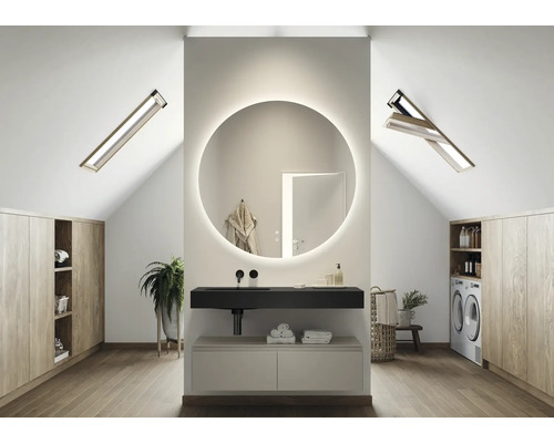 Salle de bain moderne dans les combles avec miroir rond, lavabo et fenêtres de toit.