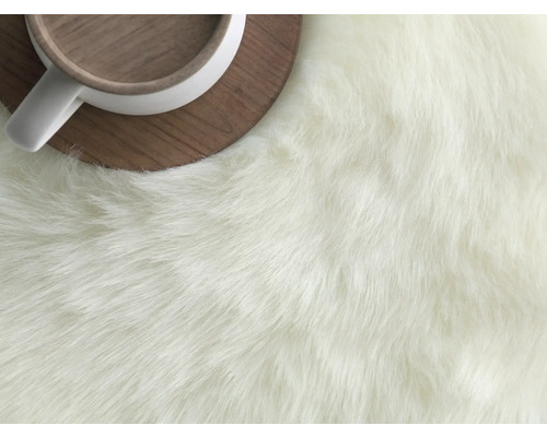 Detailansicht eines Teppichs mit langen Fasern neben einer Tasse auf einer Holzuntertasse.