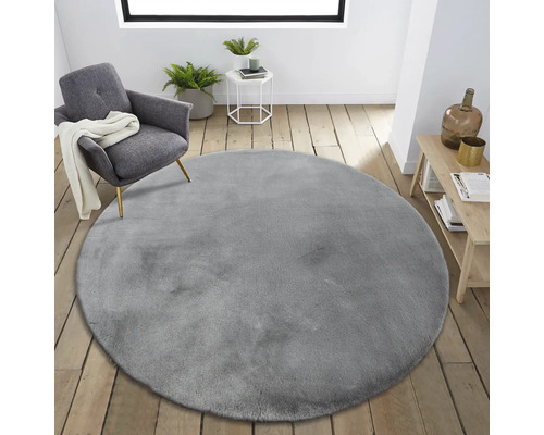Einrichtungsszene mit rundem, grauem Teppich, Sessel und Beistelltisch