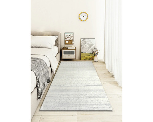 Schlafzimmer mit Bett, Nachttisch, Dekoration und einem hellen Teppich mit Muster.