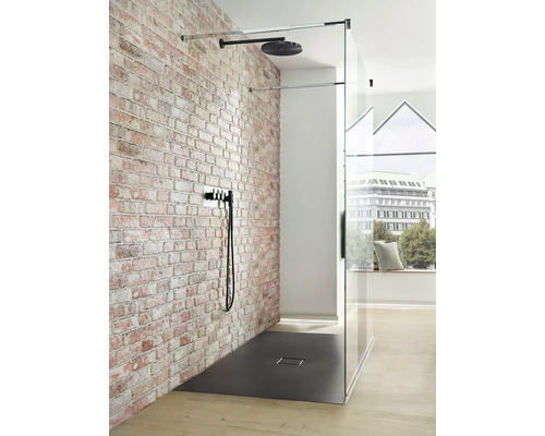 Begehbare Dusche mit Kopfbrause, Brausegarnitur und Duschwanne vor einer Ziegelwand