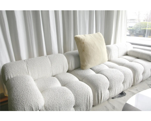 Modulares Sofa mit Kissen vor einem Fenster mit Vorhängen